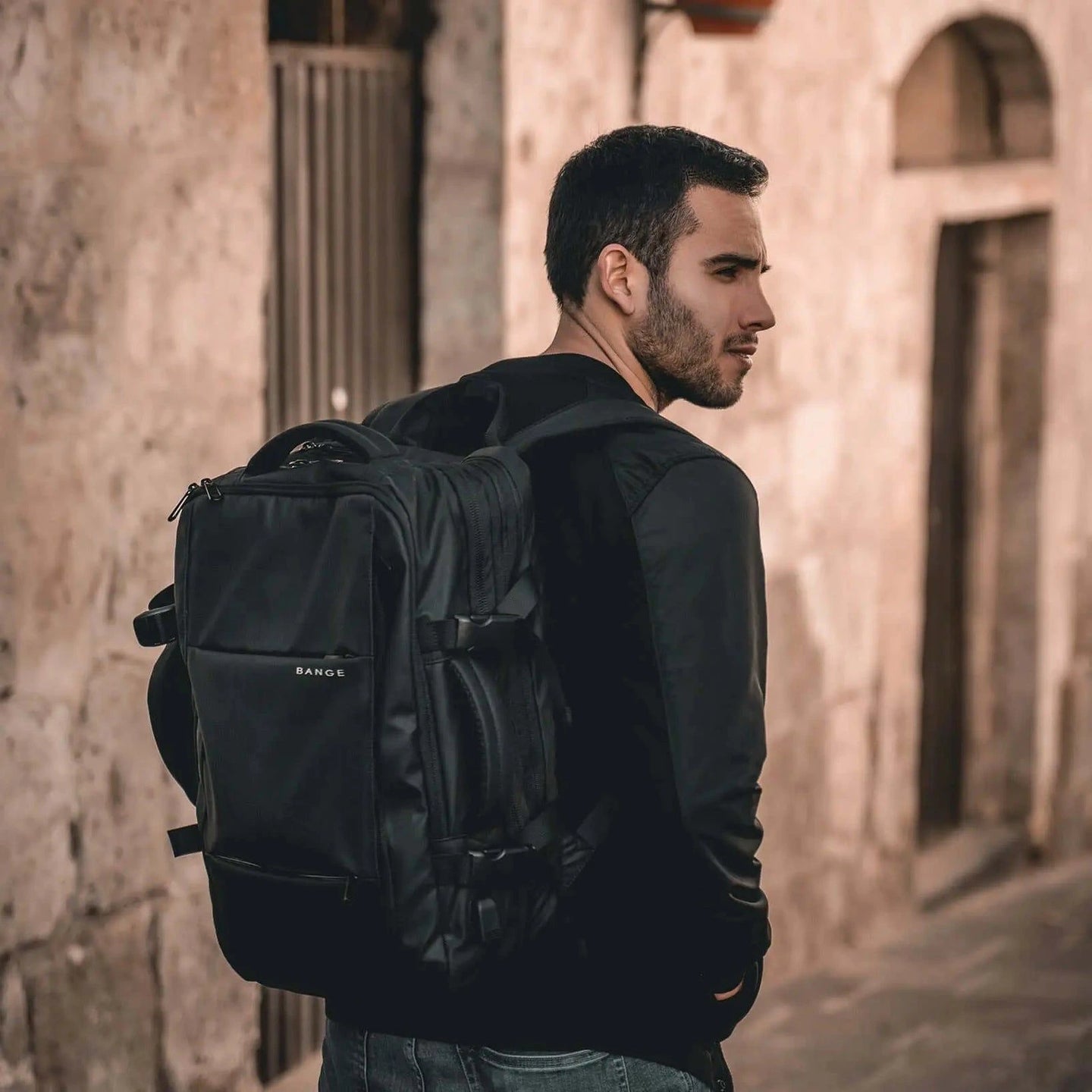 Hombre caminando por la ciudad con la mochila Bange The SafeBag en la espalda, estilo urbano moderno.