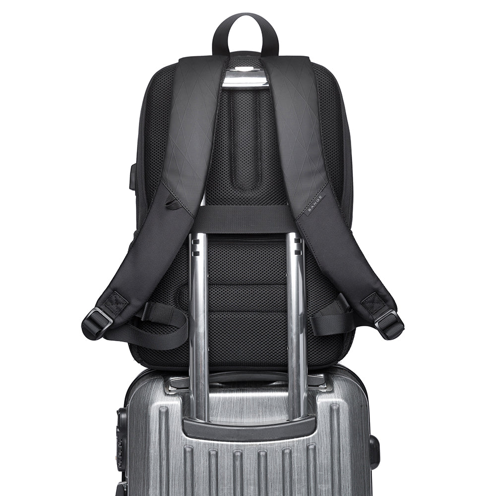 Vista posterior de la mochila The Classic de Bange colocada sobre una maleta de viaje, mostrando su banda trasera para trolley y correas acolchadas ajustables, ideal para facilitar el transporte en aeropuertos o desplazamientos largos.

