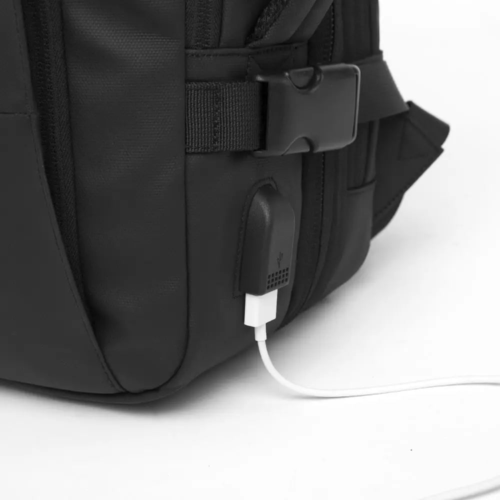 Detalle del puerto USB externo integrado en la mochila Bange The Expandable, mostrando la funcionalidad de carga para dispositivos móviles.

