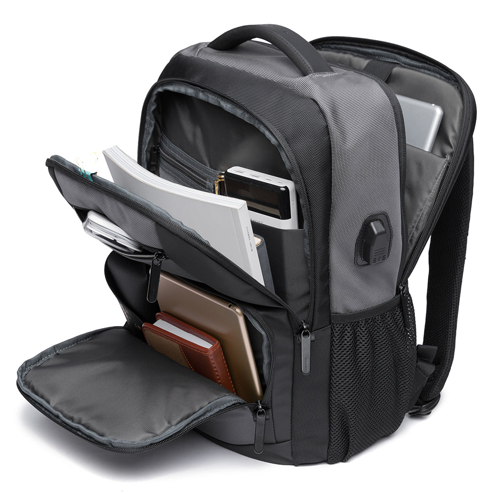 Mochila Bange The Classic gris completamente abierta, mostrando capacidad de almacenamiento con libros, tablet, cuaderno y power bank organizados en sus compartimentos.


